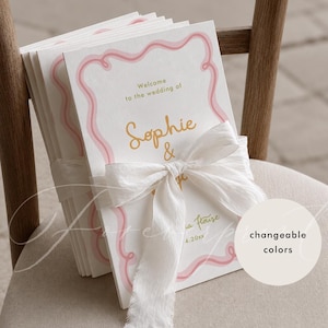 May include: A stack of white wedding programme cards featuring a pink wavy border, gold text reading Welcome to the wedding of Sophie & and a date, tied together with a white frayed silk ribbon. A circular tag displays the text changeable colours.