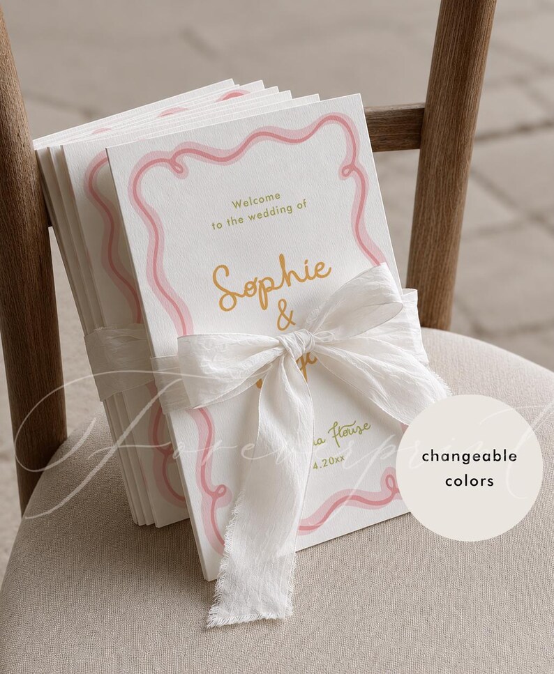 May include: A stack of white wedding programme cards featuring a pink wavy border, gold text reading Welcome to the wedding of Sophie & and a date, tied together with a white frayed silk ribbon. A circular tag displays the text changeable colours.