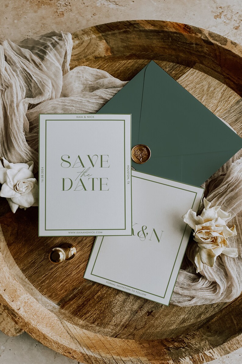 May include: Elegant wedding stationery set featuring a 'Save the Date' card with green accents, an envelope, and a wax seal. The card includes the text 'Save the Date' and the website address. Two gold rings and flowers are also present.