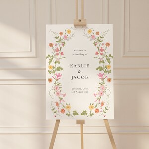 May include: A white wedding welcome sign with a floral border. The sign reads "Welcome to the wedding of Karlie & Jacob, Cleveland, Ohio, 14th August 2023."