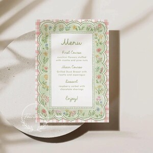 May include: A menu card with a floral design. The card has a light green border with a scalloped edge and is decorated with colorful flowers. The background is a pink and white gingham pattern. The menu includes a first course, main course, and dessert.