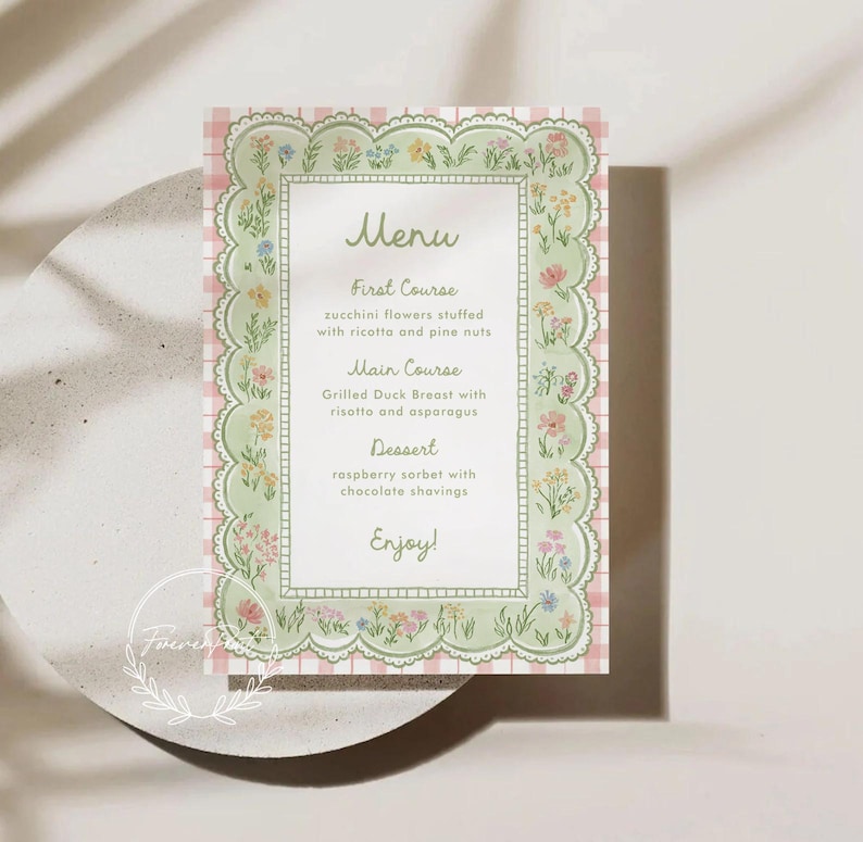 May include: A menu card with a floral design. The card has a light green border with a scalloped edge and is decorated with colorful flowers. The background is a pink and white gingham pattern. The menu includes a first course, main course, and dessert.