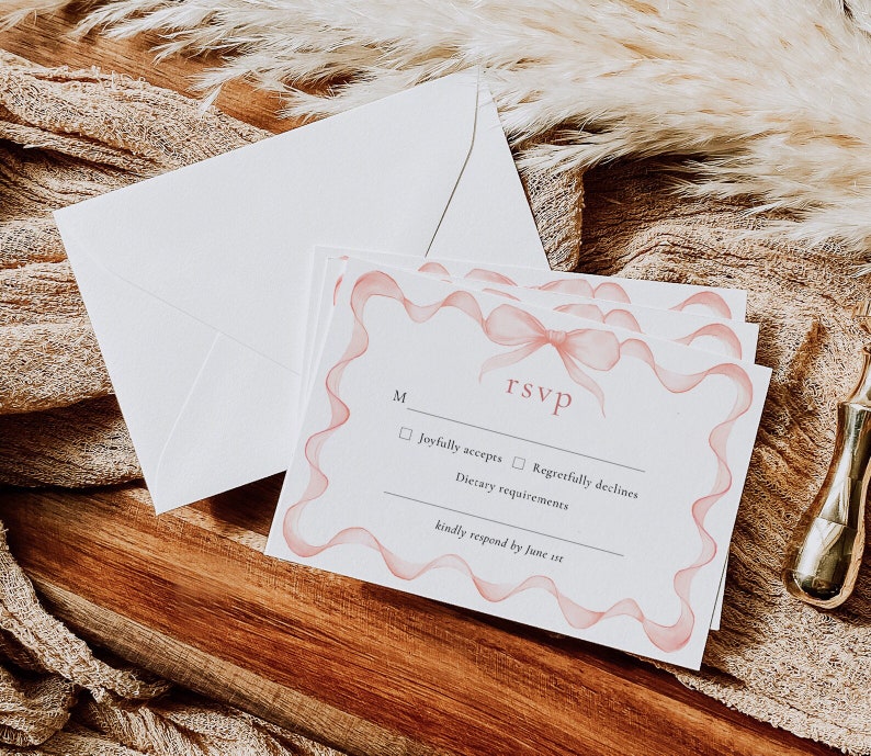 May include: RSVP card with a pink ribbon design. The card has a checkbox for "Joyfully accepts" and "Regretfully declines". It also includes a space for dietary requirements and asks for a response by June 1st.