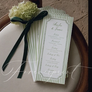 Puede incluir: Programas de ceremonia de boda con diseño de rayas verdes y blancas. Los programas están atados con una cinta verde oscuro y adornados con un pequeño ramo de flores blancas. El texto en el programa dice "Amelia & James".