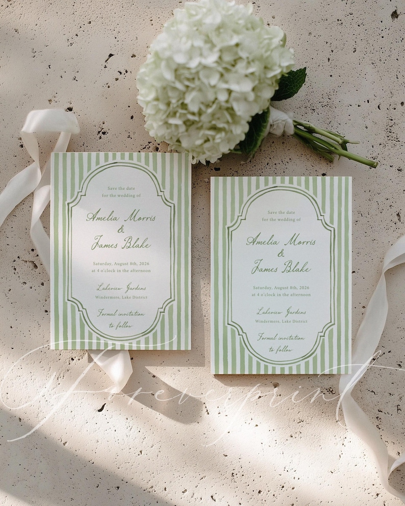 May include: Two wedding save-the-date cards with green and white striped patterns. The cards display the names "Amelia Morris & James Blake." A bouquet of white flowers and a white ribbon are also visible in the image.