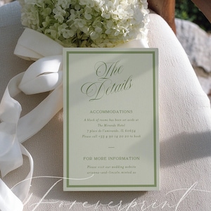 May include: A wedding invitation card with the text "The Details" in elegant script. The card has a light green border and contains accommodation details. A bouquet of white flowers and a white ribbon are in the background.