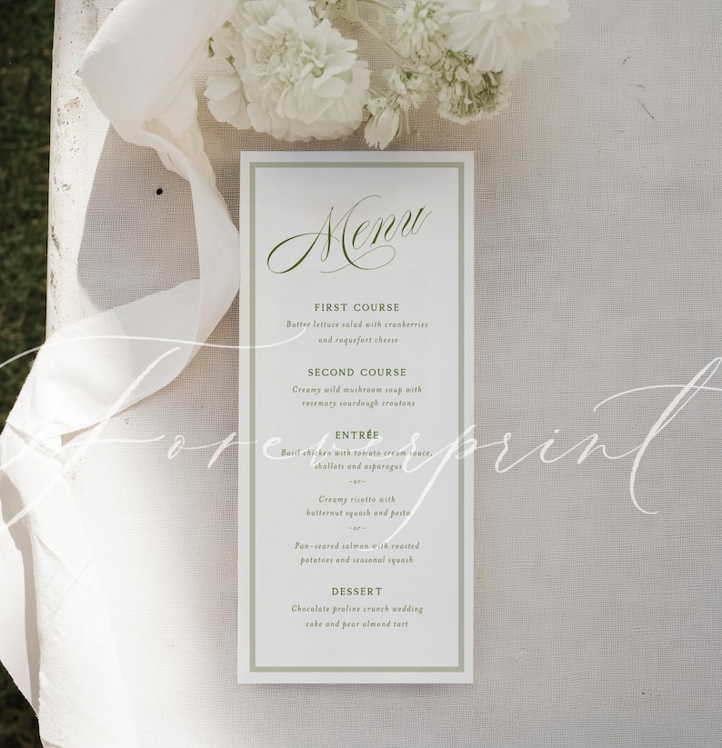 May include: A rectangular menu card with a green border and elegant script. The menu lists courses like butter lettuce salad, wild mushroom soup, basil chicken, and chocolate praline crunch cake. White flowers and a ribbon are in the background.