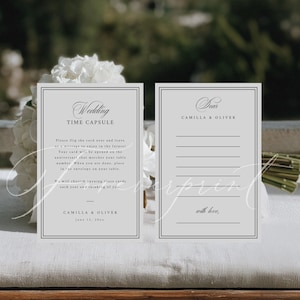 May include: Two light gray wedding time capsule cards with black text. One card reads "Wedding TIME CAPSULE" and includes instructions. The other card reads "Dear CAMILLA & OLIVER" with lines for writing. The cards are for a wedding.