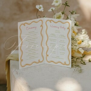 May include: A folded white wedding programme with a wavy yellow and orange border. The left side is titled Ceremony and lists the order of events. The right side is titled Wedding Party and lists the names of the participants in a serif font.