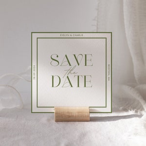 May include: A green and white save the date card with the text "Save the Date" in a modern font. The card also includes the names "Evelyn & Charlie" and the date "28.09.2024". The card is on a wooden stand and has a green border.