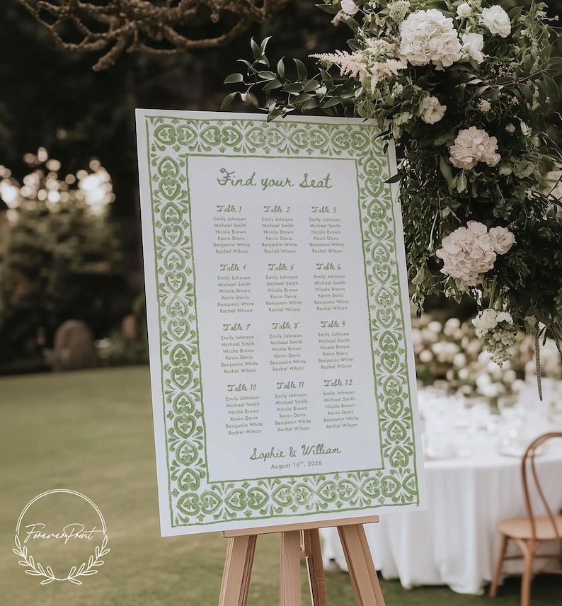May include: A white wedding seating chart with green decorative borders and text. The sign reads "Find your seat" and lists names under table numbers. The sign is displayed on a wooden easel, with flowers in the background.
