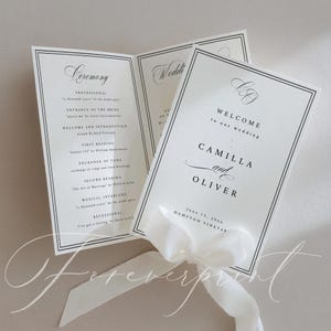 以下が含まれることがあります： 白紙に黒字で書かれたエレガントな結婚式のプログラム。白いリボンで結ばれています。「Camilla and Oliver」の名前と結婚式の詳細が記載されています。デザインには黒い縁取りと装飾的なスクリプトフォントが含まれています。
