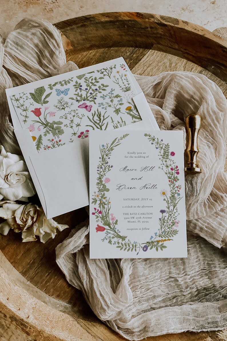 May include: A wedding invitation with a floral wreath border. The invitation is for the wedding of Mauve Hill and Bixen Neelle, on Saturday, July 15th at 2 o'clock in the afternoon at The Ritz Carlton, 3300 SW 17th Avenue, Miami, FL 33155. Reception to follow.