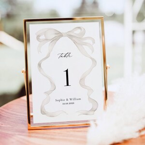 May include: White table number card with a gray watercolor bow and the text "Table 1" and "Sophie & William 18.08.2023".