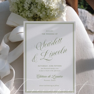 May include: A wedding invitation with a green border and elegant script. The invitation reads "Join us for the wedding of Scarlett & Lincoln" with the date, time, and location: Chateau de Lumi&egrave;re, Provence, France. A bouquet of white flowers and ribbon are in the background.