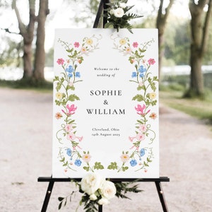 May include: A white wedding welcome sign with a floral border. The sign reads "Welcome to the wedding of Sophie & William, Cleveland, Ohio, 14th August 2023".