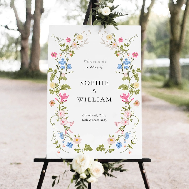 May include: A white wedding welcome sign with a floral border. The sign reads "Welcome to the wedding of Sophie & William, Cleveland, Ohio, 14th August 2023".