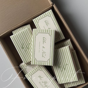 May include: A collection of matchboxes with green and white striped patterns and decorative labels. The labels feature the names "Chloe & Nich" and the date "September 07, 2023". The box also contains the text "the Perfect MATCH".