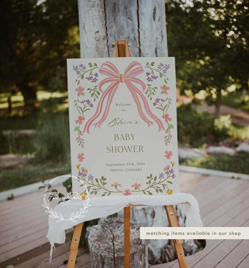 May include: A welcome sign for a baby shower with a pink bow and floral border. The sign reads "Welcome to Blaire's Baby Shower September 25th, 2026 Denver, Colorado".