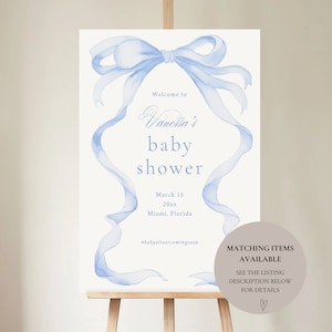 May include: A blue watercolor ribbon bow with a white background. The text reads "Welcome to Vanessa's baby shower March 15 20xx Miami, Florida #babyolivercomingsoon".