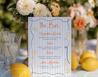May include: A bar menu sign with a light blue and white striped background. The menu lists signature drinks, wine, beer, and non-alcoholic beverages. Lemons and a floral arrangement are in the foreground.