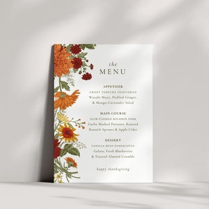 Pu&ograve; includere: Un menu del Ringraziamento con un bordo floreale. Il menu include antipasti, piatto principale e dessert. Il testo recita: "the MENU, APPETIZER, CRISPY TEMPURA VEGETABLES, Wasabi Mayo, Pickled Ginger, & Mango-Coriander Salad, MAIN COURSE, SLOW-COOKED BOURBON PORK, Garlic Mashed Potatoes, Roasted Brussels Sprouts & Apple Cider, DESSERT, VANILLA BEAN PANNACOTTA, Gelato, Fresh Blueberries & Toasted Almond Crumble, happy thanksgiving"