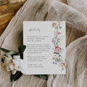 May include: A white card with black text and floral illustrations. The text reads "Details" and includes information about a wedding ceremony, reception, and accommodations. The card is on a beige fabric background.