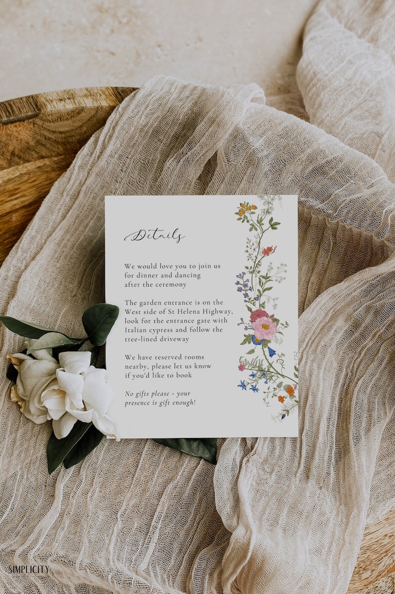May include: A white card with black text and floral illustrations. The text reads "Details" and includes information about a wedding ceremony, reception, and accommodations. The card is on a beige fabric background.