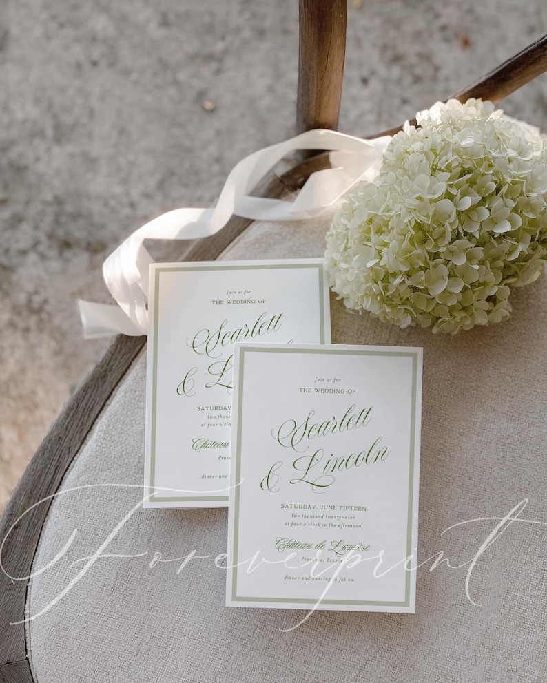 May include: Two wedding invitations with green text and borders, featuring the names "Scarlett & Lincoln" and event details. A white ribbon and a bouquet of white flowers are in the background. The text includes "Saturday, June Fifteen".