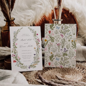 May include: Two wedding invitations. One features a floral wreath with text, including names and date. The other has a floral pattern with butterflies. The invitations are on a textured surface with decorative elements.