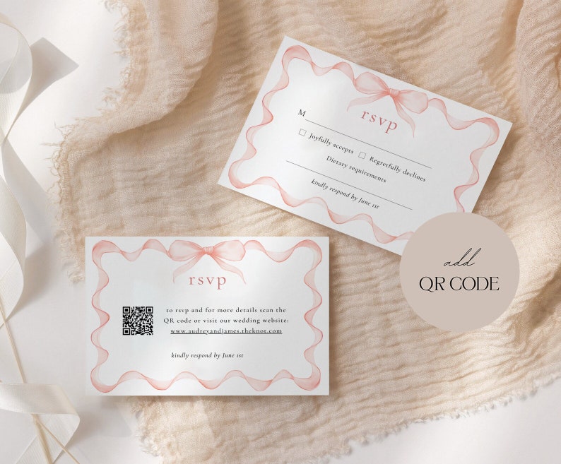 May include: A white RSVP card with a pink ribbon design. The card has a QR code and the text "to rsvp and for more details scan the QR code or visit our wedding website: www.audreyandjames.theknot.com kindly respond by June 1st".