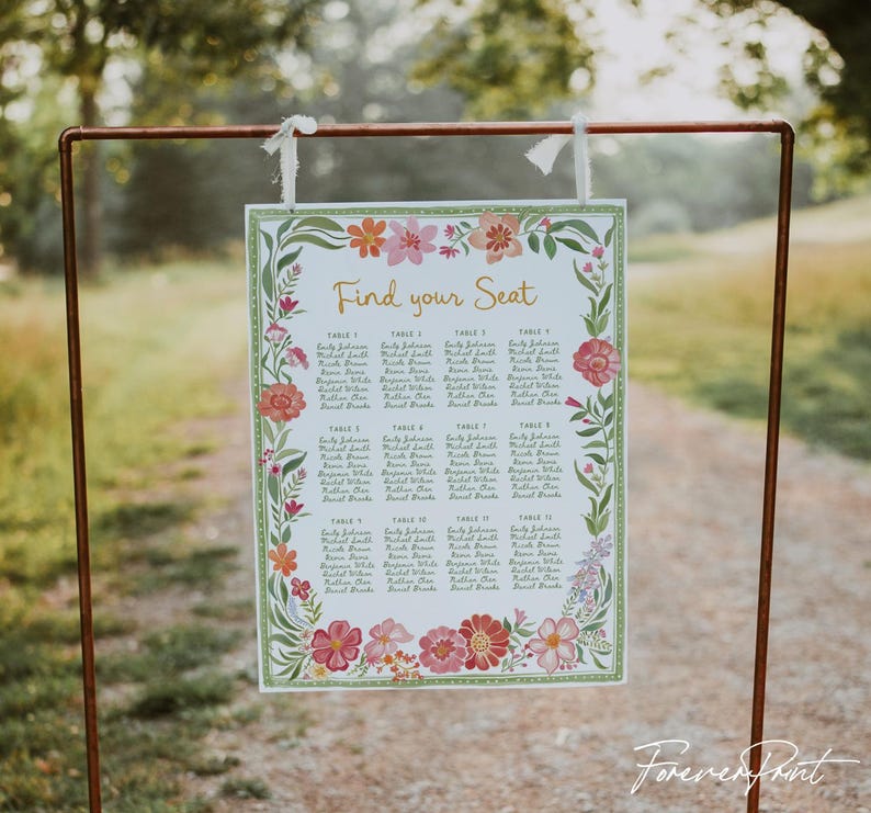 May include: A floral wedding seating chart with the text "Find your Seat" in gold script. The chart is framed with a green border and adorned with pink, orange, and white flowers. The names of the guests are listed under the table numbers.