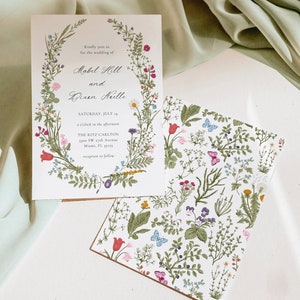 May include: Wedding invitation with floral design. The invitation features the names "Mabel Holl" and "Dixen Neelle" with the date "Saturday, July 14". The invitation is surrounded by a floral wreath and includes the venue address.