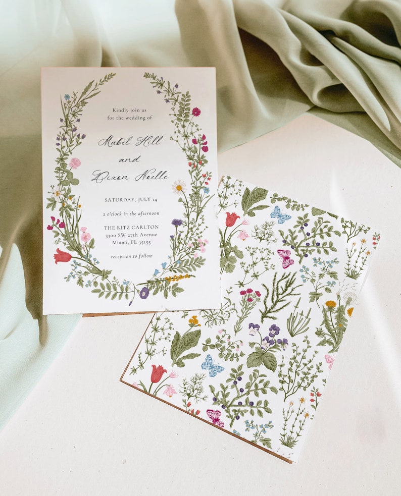 May include: Wedding invitation with floral design. The invitation features the names "Mabel Holl" and "Dixen Neelle" with the date "Saturday, July 14". The invitation is surrounded by a floral wreath and includes the venue address.