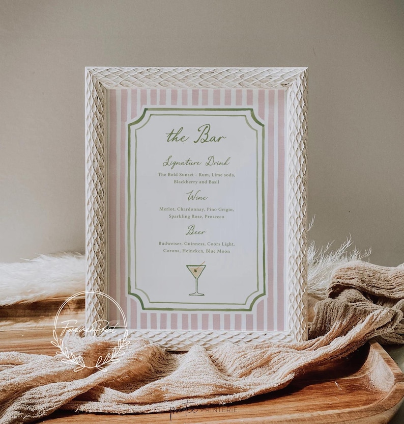 May include: A framed sign with a pink and white striped background and a decorative border. The sign reads "the Bar" and lists drink options: Signature Drink, Wine, and Beer. A cocktail illustration is at the bottom.