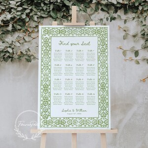 May include: A wedding seating chart on an easel. The chart has a green decorative border and lists names under the heading "Find your Seat." The names are organized by table number. The names Sophie & William and the date August 16th, 2016 are at the bottom.