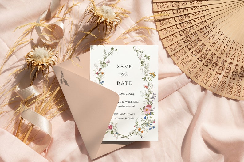 K&ouml;nnte beinhalten: Eine Save-the-Date-Karte mit einem floralen Kranzdesign. Die Karte ist wei&szlig; mit einem hellblauen Rand und Text, der "Save the Date" und "9.06.2024" lautet. Der Text lautet auch "Le & William getting married Tuscany, Italy invitation to follow".