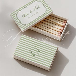 May include: Two matchboxes, one open and one closed, with a light green and white striped design. The open box reveals matches with pink tips. The top of the open box has the names "Chloe & Nich" and the date "September 07, 20xx". The closed box has the initials "C & N".