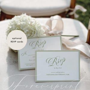 May include: Two white RSVP cards with green borders and elegant script, one with the word "RSVP" and the other with a website address. A white floral arrangement and the words "optional RSVP cards" are also visible.