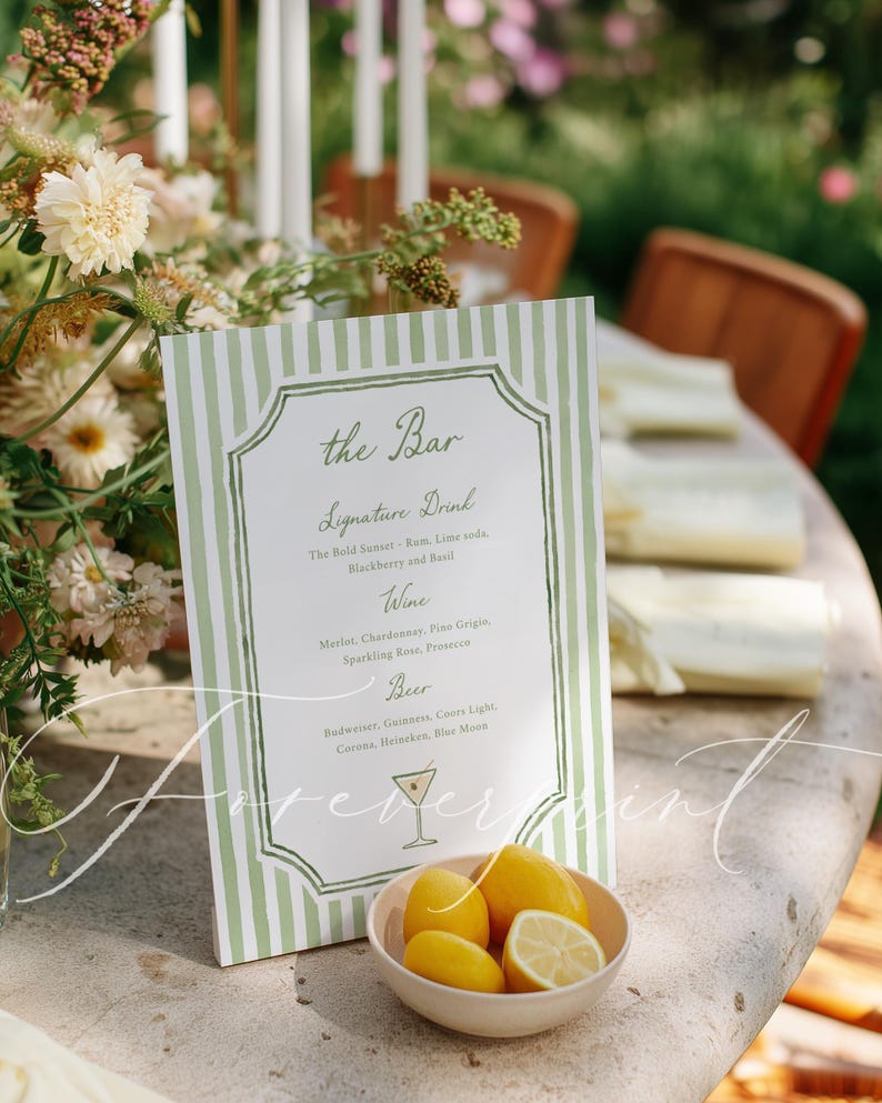May include: A bar menu with a green and white striped background, featuring a list of drinks. A small bowl of lemons sits in front of the menu. The text on the menu includes "the Bar" and drink options.
