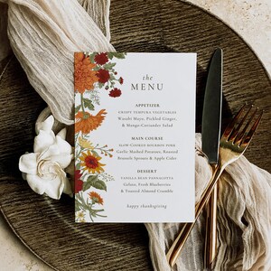 Pu&ograve; includere: Un menu di ringraziamento con un design floreale in tonalit&agrave; arancio, rosso e verde. Il menu include opzioni di antipasti, piatti principali e dessert. Il testo recita "the MENU", "APPETIZER", "CRISPY TEMPURA VEGETABLES Wasabi Mayo, Pickled Ginger, & Mango-Coriander Salad", "MAIN COURSE", "SLOW-COOKED BOURBON PORK Garlic Mashed Potatoes, Roasted Brussels Sprouts & Apple Cider", "DESSERT", "VANILLA BEAN PANNACOTTA Gelato, Fresh Blueberries & Toasted Almond Crumble", e "happy thanksgiving".