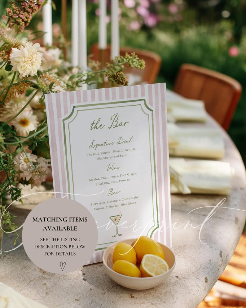 May include: A pink and white striped bar menu with a decorative border, listing signature drinks, wine, and beer options. A small bowl of lemons sits in front of the menu. Text on the menu includes "the Bar" and "Matching Items Available".