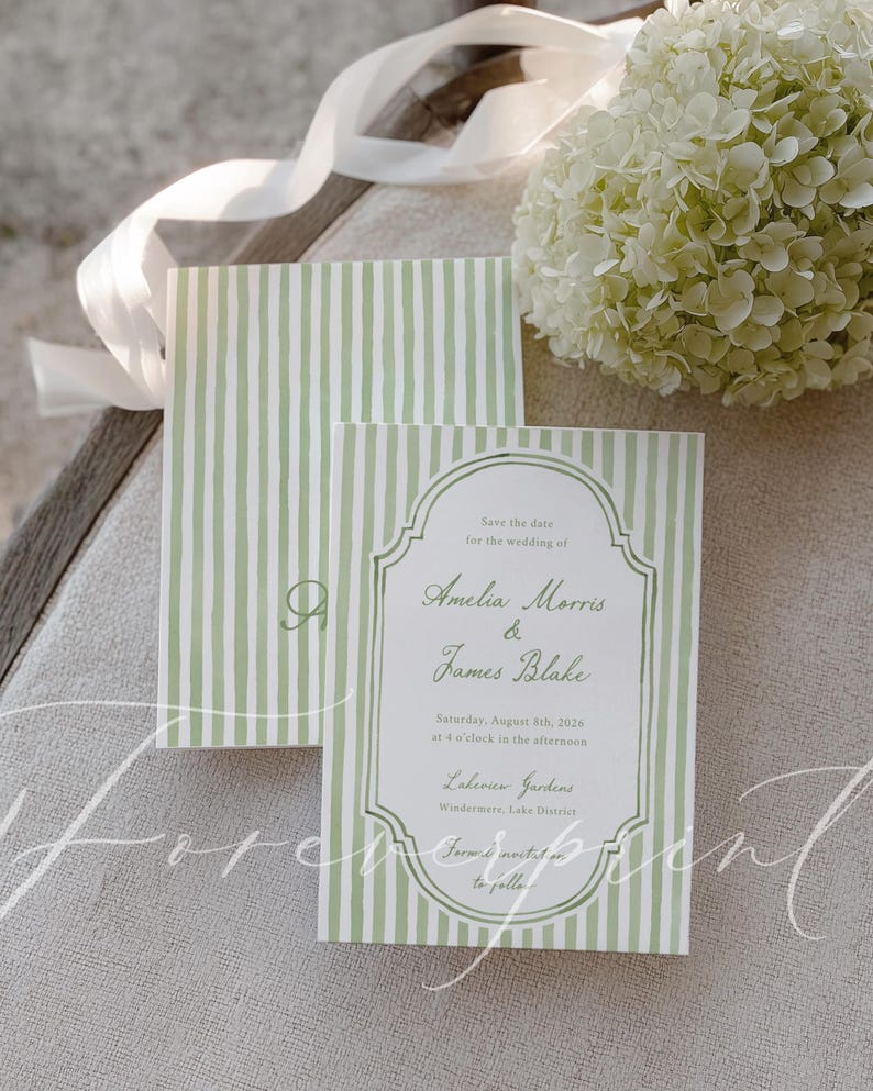 May include: Wedding invitation with a green and white striped pattern. The text reads "Save the date for the wedding of Amelia Morris & James Blake, Saturday, August 8th, 2026". A bouquet of white flowers and ribbon are in the background.