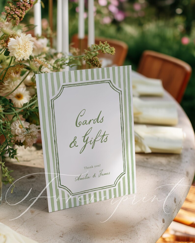 May include: A rectangular sign with green and white striped borders and the words "Cards & Gifts" in elegant script. The sign also includes the names "Amelia & James" and the words "Thank you!" in a wedding setting.