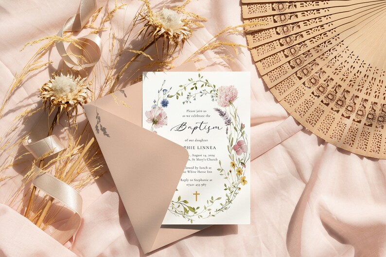 Peut inclure: Une carte d'invitation blanche avec une bordure de couronne florale et une croix dor&eacute;e. Le texte indique "Veuillez nous rejoindre pour c&eacute;l&eacute;brer le bapt&ecirc;me de notre fille Sophie Linnea le 14 ao&ucirc;t 2023 &agrave; l'&eacute;glise St. Mary's, suivi d'un d&eacute;jeuner &agrave; The White House Inn. R&eacute;pondez &agrave; Sophie &agrave; (email uniquement)"