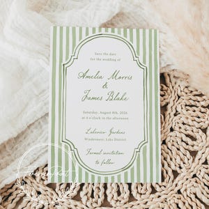 May include: A wedding invitation with a green and white striped design. The text reads "Save the date for the wedding of Amelia Morris & James Blake" with the date, time, and location. The invitation is on a woven placemat.