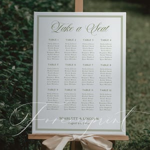 Puede incluir: Un plano de asientos de boda en un caballete de madera. El letrero dice "Take a Seat" en escritura elegante. Los nombres de los invitados se enumeran debajo de los números de mesa. La fecha de la boda es el 21 de agosto de 2015. Un lazo color crema adorna el caballete.