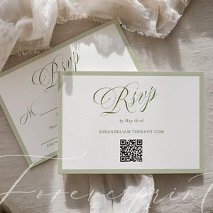 May include: Two white RSVP cards with a sage green border and elegant script. The cards include the text "RSVP by May third" and a QR code. The background is a neutral linen fabric.