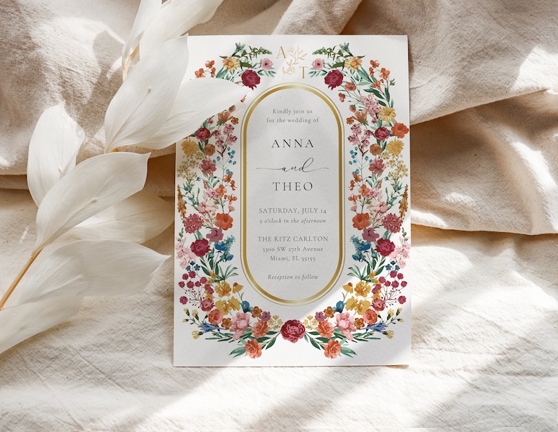 May include: A wedding invitation with a floral border in shades of pink, red, orange, yellow, and blue. The invitation reads "Kindly join us for the wedding of Anna and Theo, Saturday, July 14, 2 o'clock in the afternoon, The Ritz Carlton, 1100 SW 27th Avenue, Miami, FL 33155, Reception to follow."