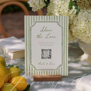 May include: A wedding sign with the text "Share the Love" in elegant script, featuring a QR code for photo sharing. The sign has a green and white striped background and is displayed on a wooden base. Lemons and flowers are in the background.